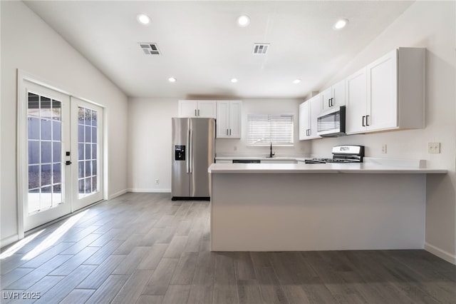 kitchen featuring stainless steel appliances, french doors, visible vents, and a peninsula