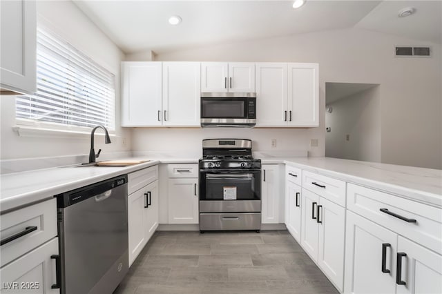 kitchen with lofted ceiling, stainless steel appliances, a sink, and visible vents