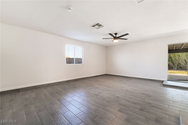 unfurnished room with baseboards, visible vents, dark wood finished floors, and a ceiling fan