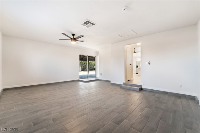 spare room featuring ceiling fan, visible vents, dark wood finished floors, and baseboards