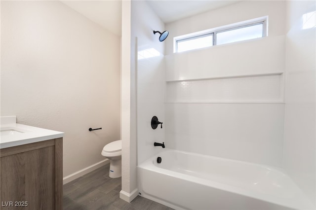 bathroom featuring baseboards, toilet, vanity, wood finished floors, and shower / bathtub combination