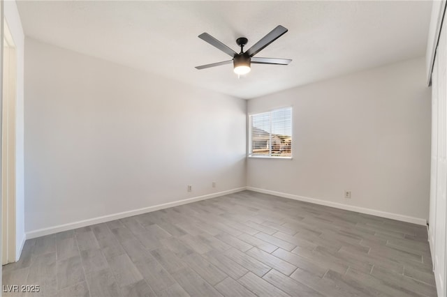 spare room featuring baseboards, ceiling fan, and light wood finished floors