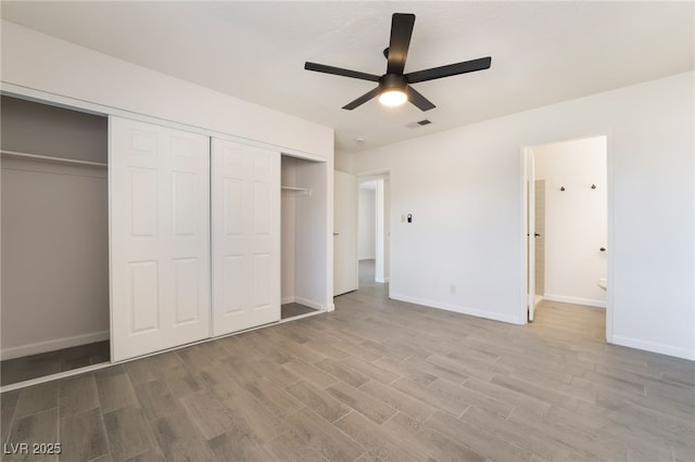 unfurnished bedroom with baseboards, a closet, visible vents, and wood finished floors