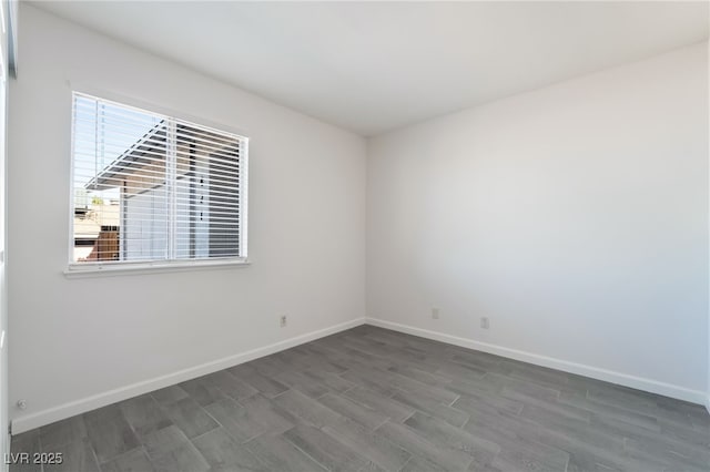 spare room with baseboards and wood finished floors