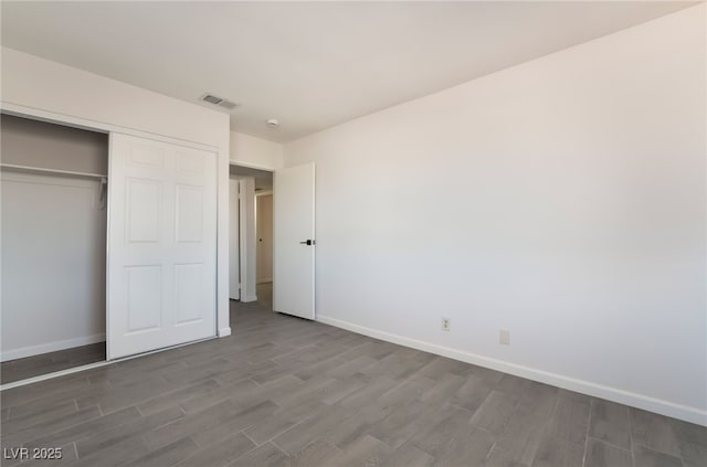 unfurnished bedroom with baseboards, a closet, visible vents, and wood finished floors