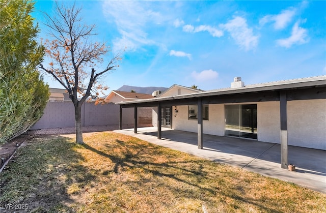 back of property featuring fence, a yard, stucco siding, a chimney, and a patio area