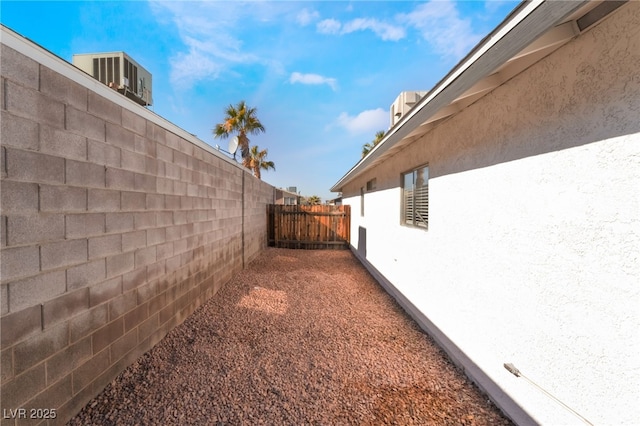 view of property exterior with fence, central AC unit, and stucco siding