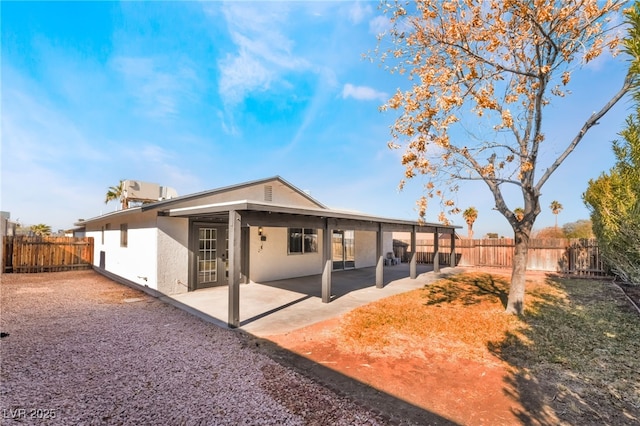 rear view of house featuring a patio area, a fenced backyard, and stucco siding