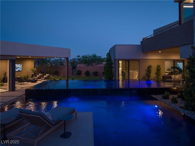 pool at dusk with a patio area