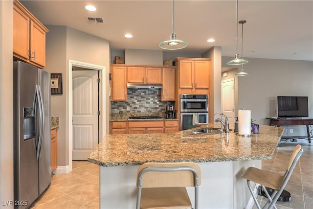 kitchen featuring stainless steel appliances, decorative light fixtures, a kitchen breakfast bar, and sink