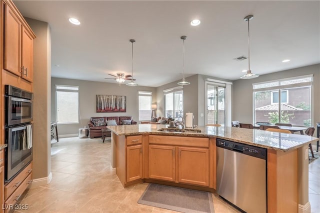 kitchen with sink, light stone countertops, an island with sink, and appliances with stainless steel finishes