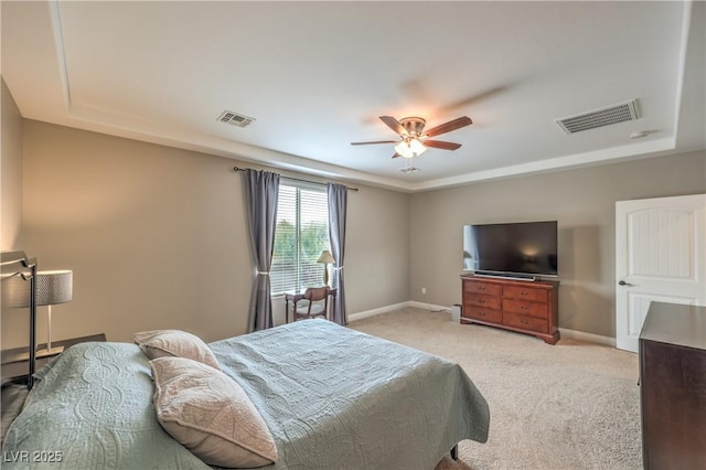 bedroom with light carpet, a raised ceiling, and ceiling fan