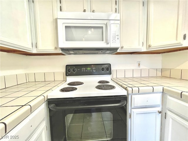 kitchen featuring range with electric cooktop, white cabinetry, and tile countertops