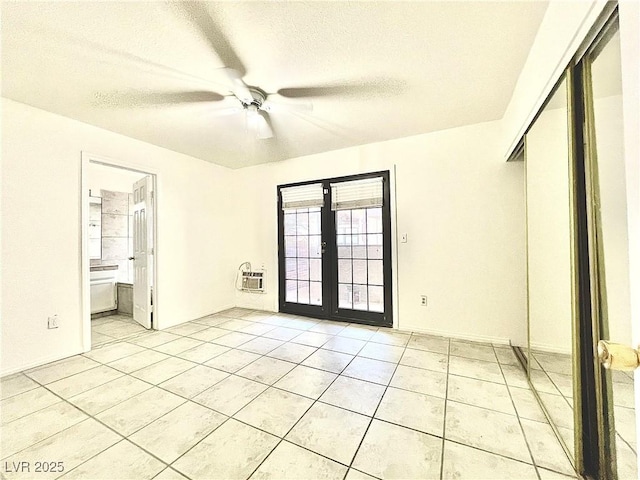 tiled spare room featuring a textured ceiling, ceiling fan, and french doors