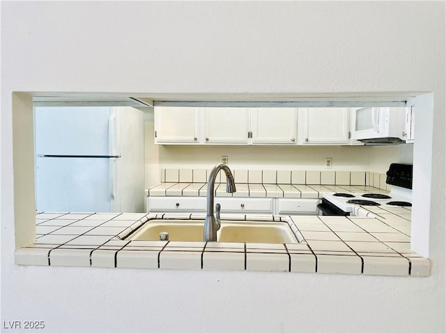 kitchen featuring white cabinetry, tile countertops, and white appliances