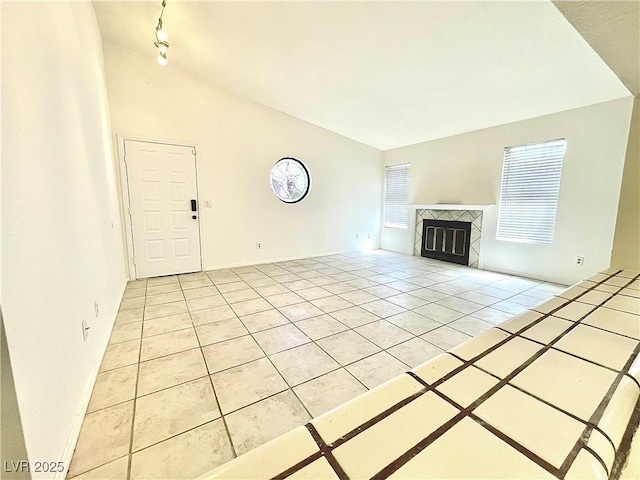 unfurnished living room with a tiled fireplace, light tile patterned floors, high vaulted ceiling, and rail lighting