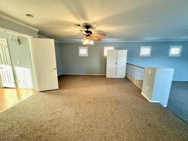 carpeted spare room with a wealth of natural light, ornamental molding, and ceiling fan