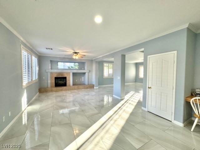 unfurnished living room with ornamental molding, ceiling fan, and a fireplace