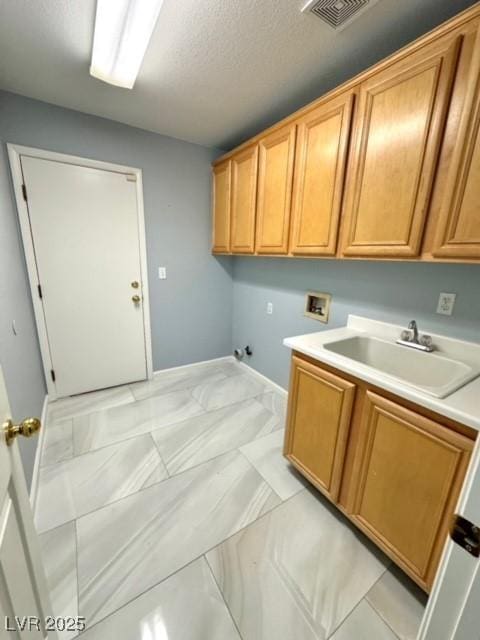 laundry area featuring sink, gas dryer hookup, cabinets, a textured ceiling, and washer hookup