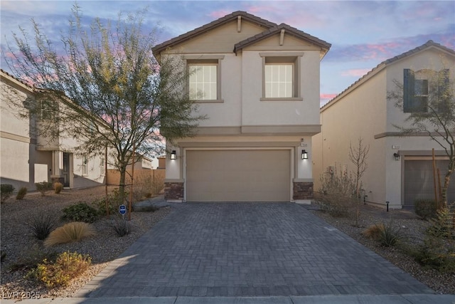 view of front facade with a garage, a tile roof, decorative driveway, and stucco siding