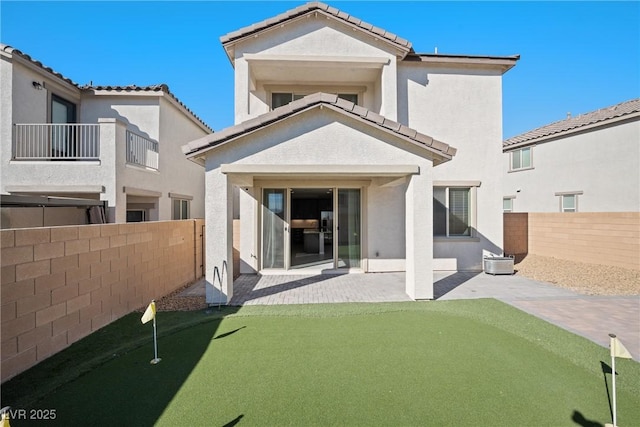 back of property with a fenced backyard, a tile roof, a patio, and stucco siding