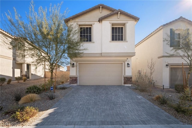 view of front of property featuring a garage, decorative driveway, a tile roof, and stucco siding