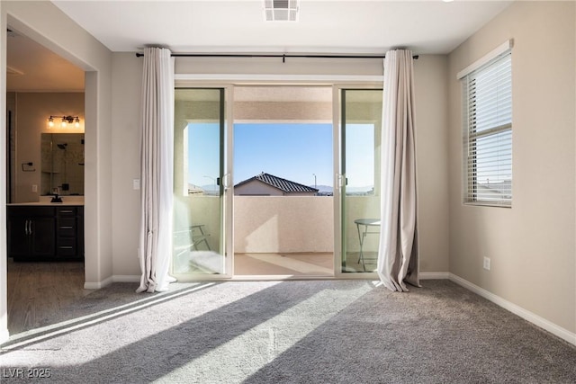 entryway featuring carpet floors, a sink, visible vents, and baseboards