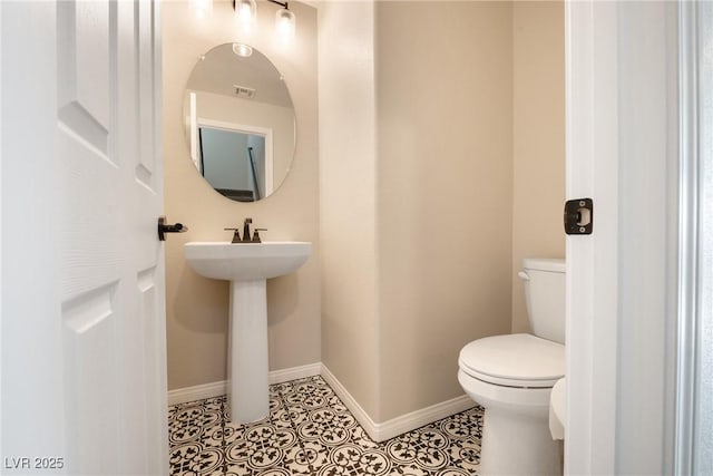 half bath with toilet, baseboards, a sink, and tile patterned floors