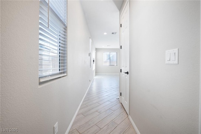 corridor with wood tiled floor, visible vents, and baseboards