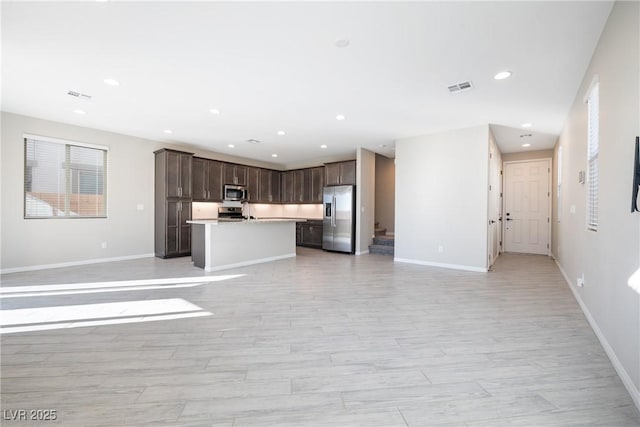 unfurnished living room featuring baseboards, visible vents, and recessed lighting