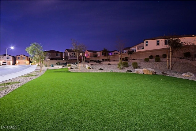 yard at night featuring a residential view