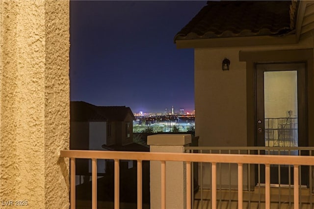 balcony at night featuring a view of city lights