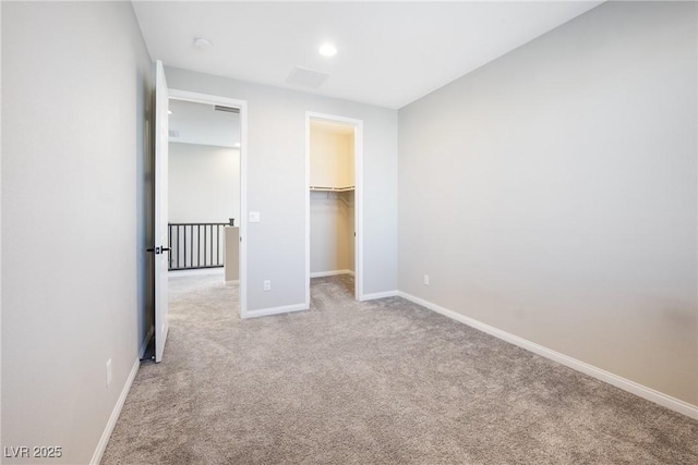 unfurnished bedroom featuring a spacious closet, a closet, carpet, and baseboards