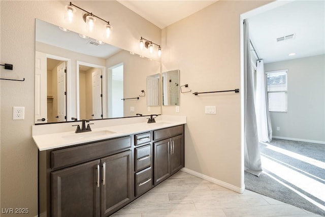 full bathroom featuring visible vents, a sink, baseboards, and double vanity