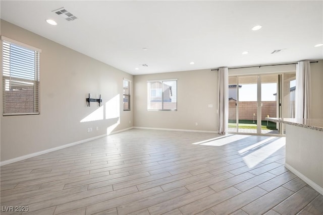 unfurnished room with light wood-type flooring, visible vents, plenty of natural light, and baseboards