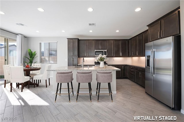 kitchen with appliances with stainless steel finishes, visible vents, a sink, and dark brown cabinetry