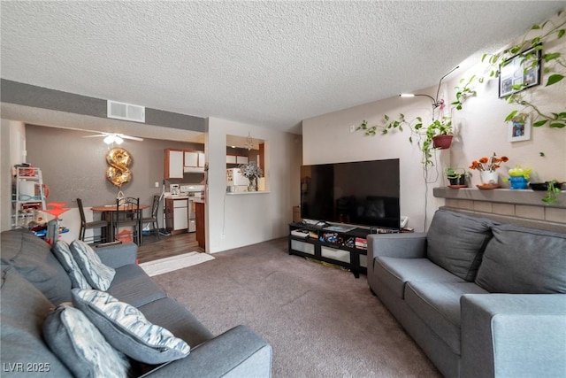 living room featuring ceiling fan, dark carpet, and a textured ceiling