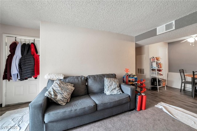 living room with ceiling fan, hardwood / wood-style floors, and a textured ceiling