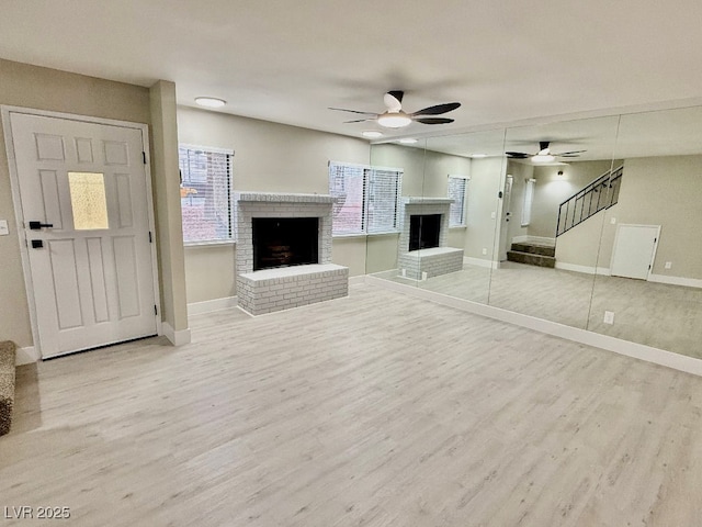 unfurnished living room with hardwood / wood-style flooring, ceiling fan, and a brick fireplace