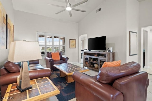 tiled living room with ceiling fan and high vaulted ceiling