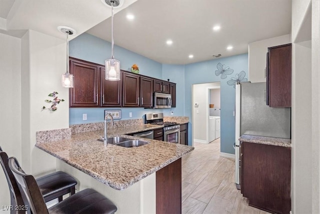 kitchen with hanging light fixtures, appliances with stainless steel finishes, sink, and kitchen peninsula