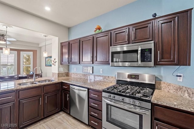 kitchen with pendant lighting, sink, dark brown cabinetry, light stone counters, and stainless steel appliances