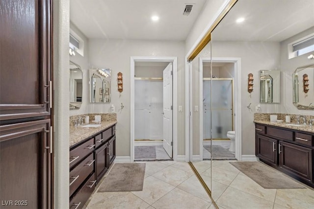 bathroom with vanity, a shower with door, and toilet