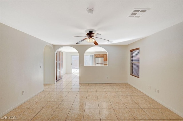 tiled empty room featuring plenty of natural light and ceiling fan