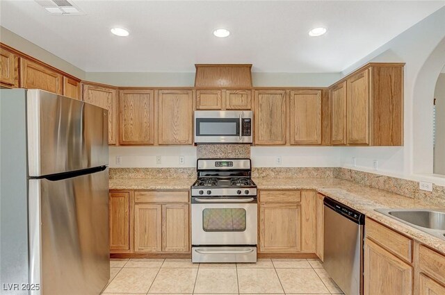 kitchen with light stone countertops, light tile patterned flooring, appliances with stainless steel finishes, and light brown cabinetry