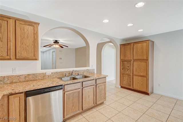 kitchen featuring sink, stainless steel dishwasher, light tile patterned floors, ceiling fan, and light stone counters