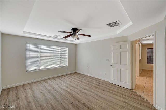 empty room featuring ceiling fan, a raised ceiling, and light hardwood / wood-style flooring