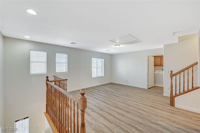 spare room with washer / dryer and light hardwood / wood-style floors