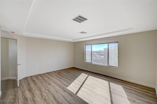 unfurnished room with a raised ceiling and light hardwood / wood-style flooring