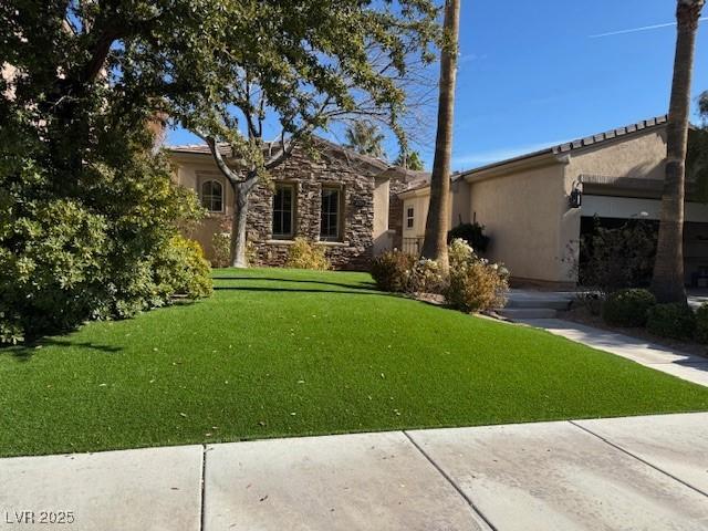 ranch-style house featuring a garage, stone siding, a front lawn, and stucco siding